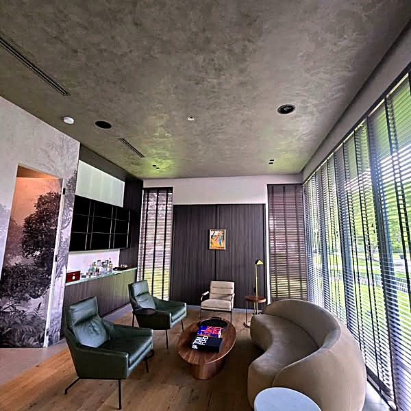 Living room with green chairs, a curved beige sofa and a textured Venetian plaster ceiling