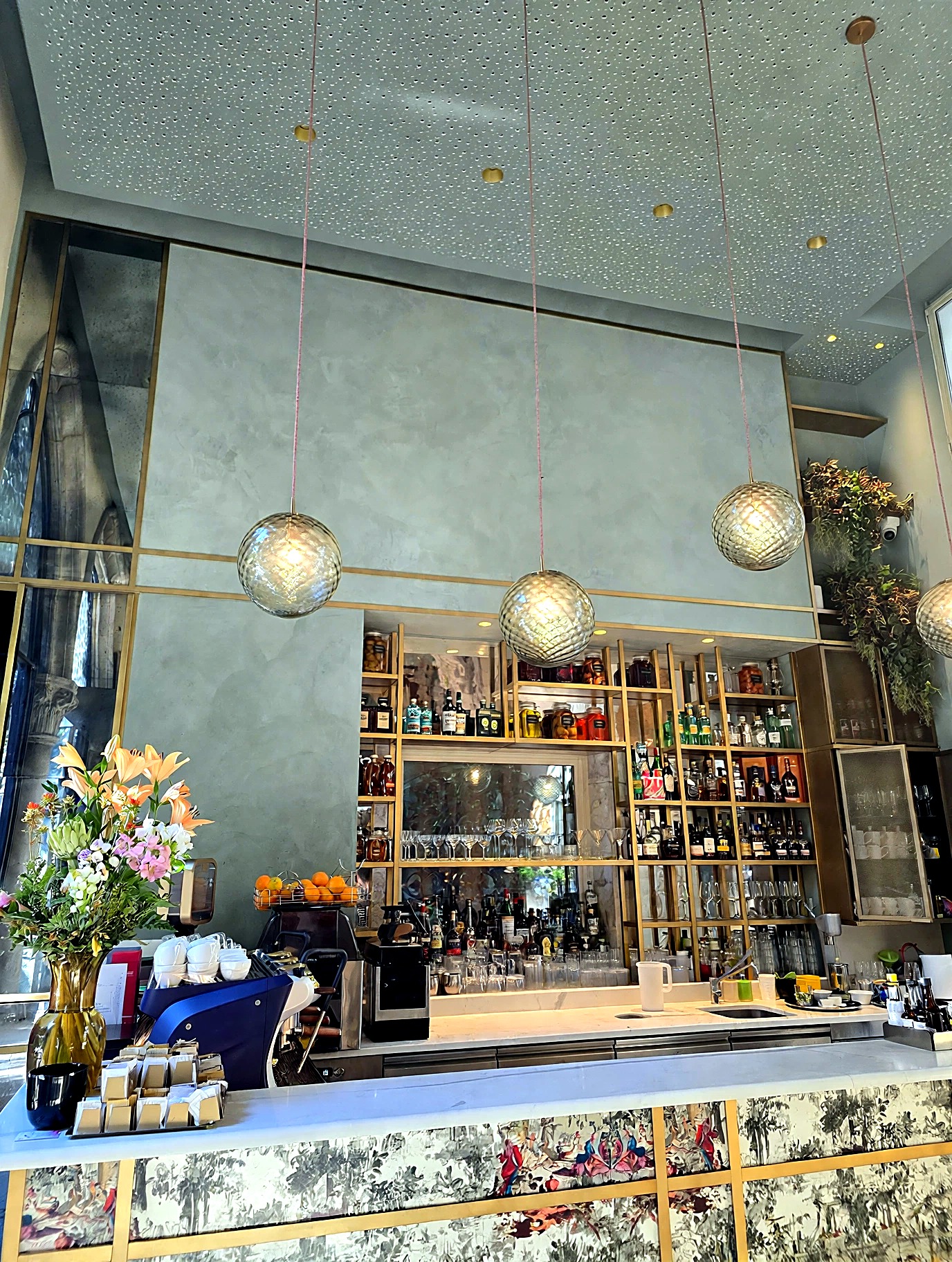 Café bar with sage-toned Venetian plaster walls and brass detailing