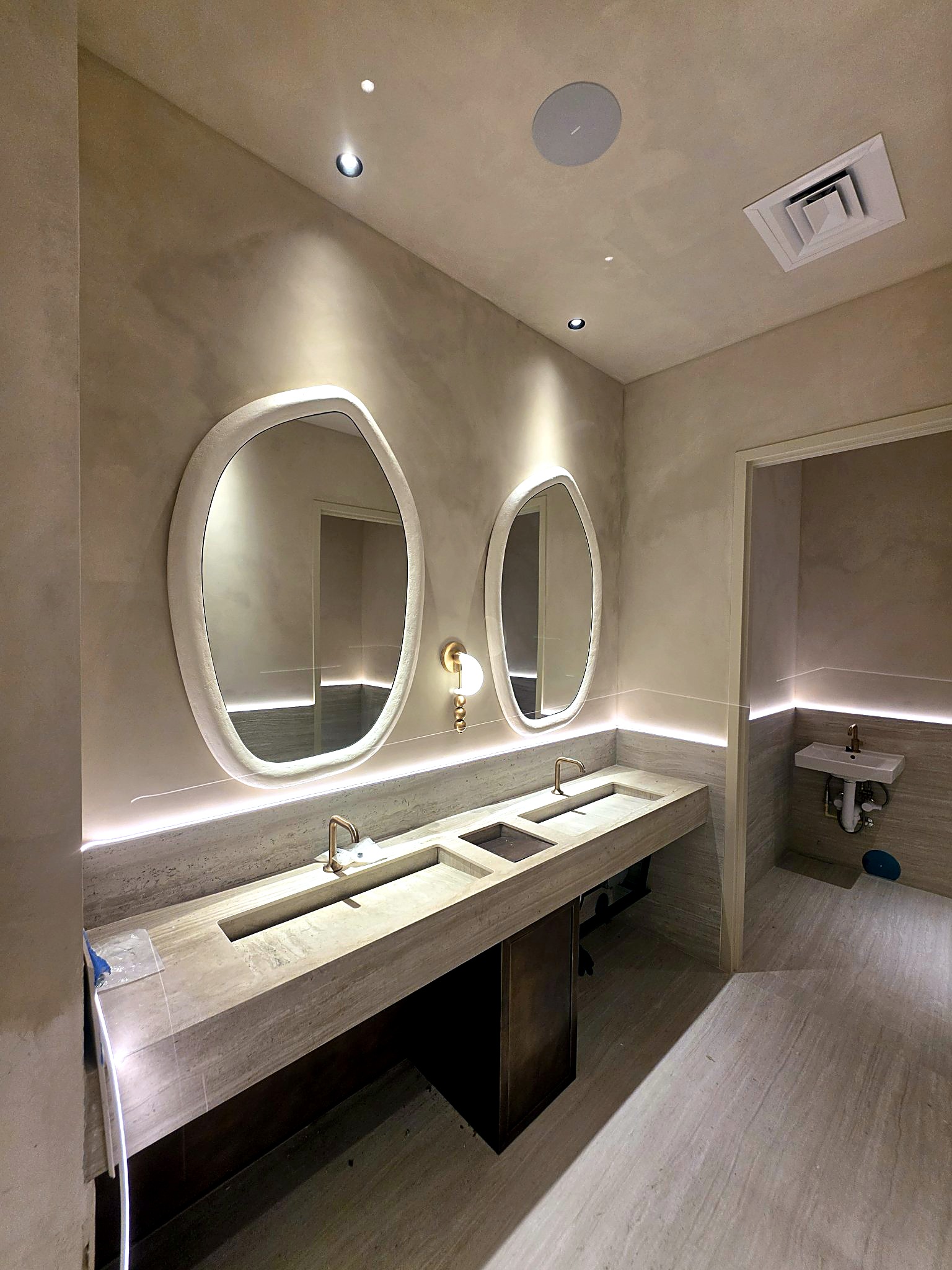 Completed limewash bathroom with softly layered walls and illuminated sculptural mirrors